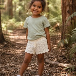 girl in kids on trend cream lacey shorts and green tshirt standing in a forest