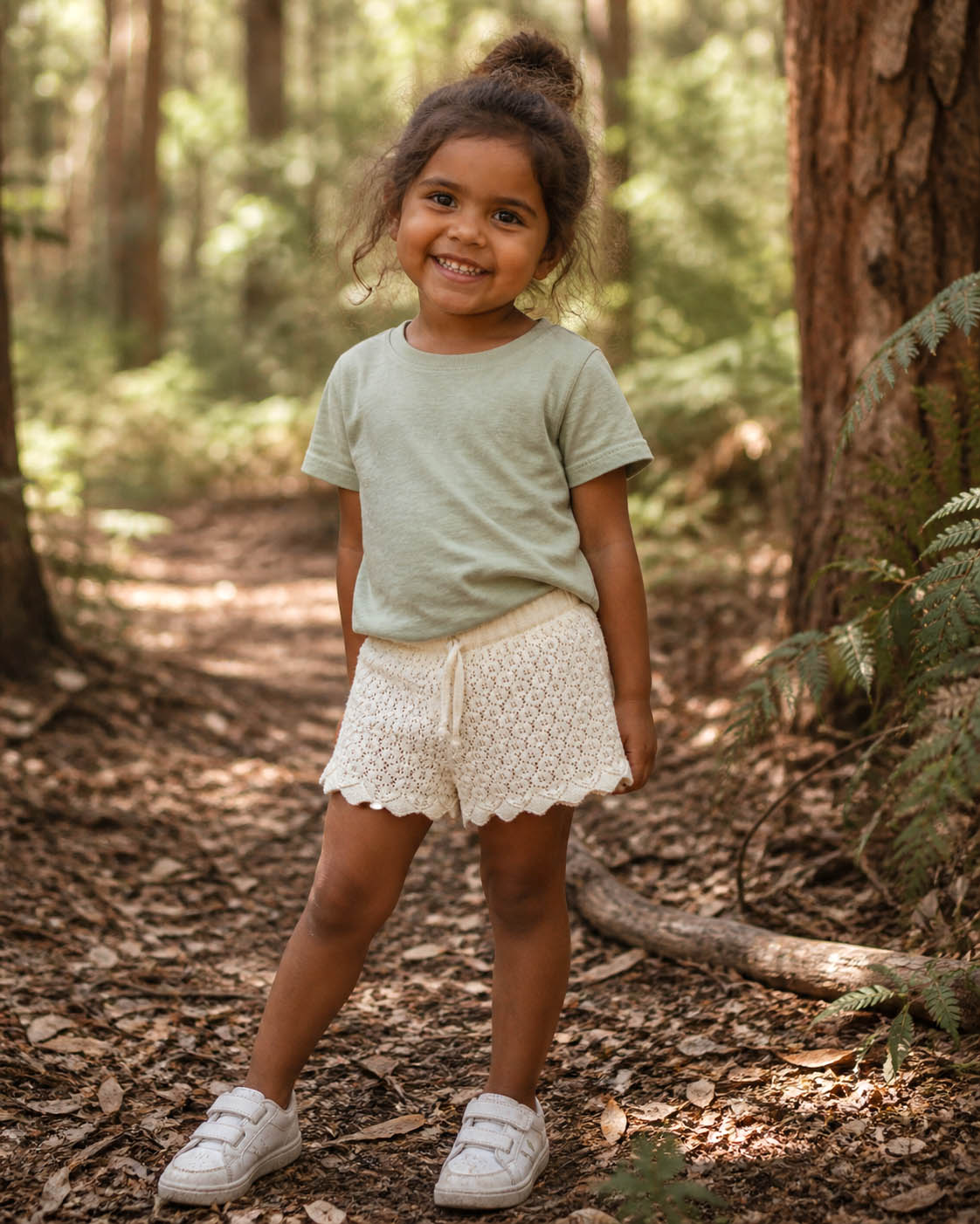 girl in kids on trend cream lacey shorts and green tshirt standing in a forest