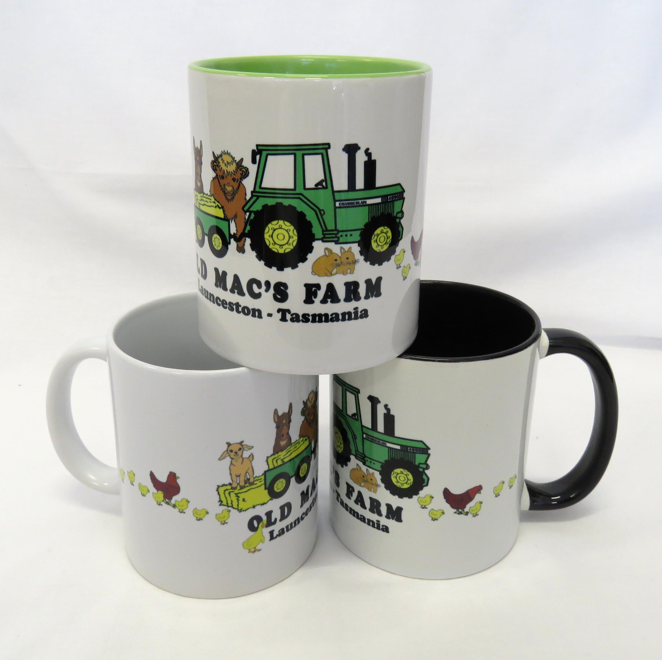 three old macs coffee mugs in green, white and black with cartoon style green tractor and animals