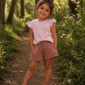 girl wearing a pink tshirt and kids on trend plum pink shorts standing in a forest